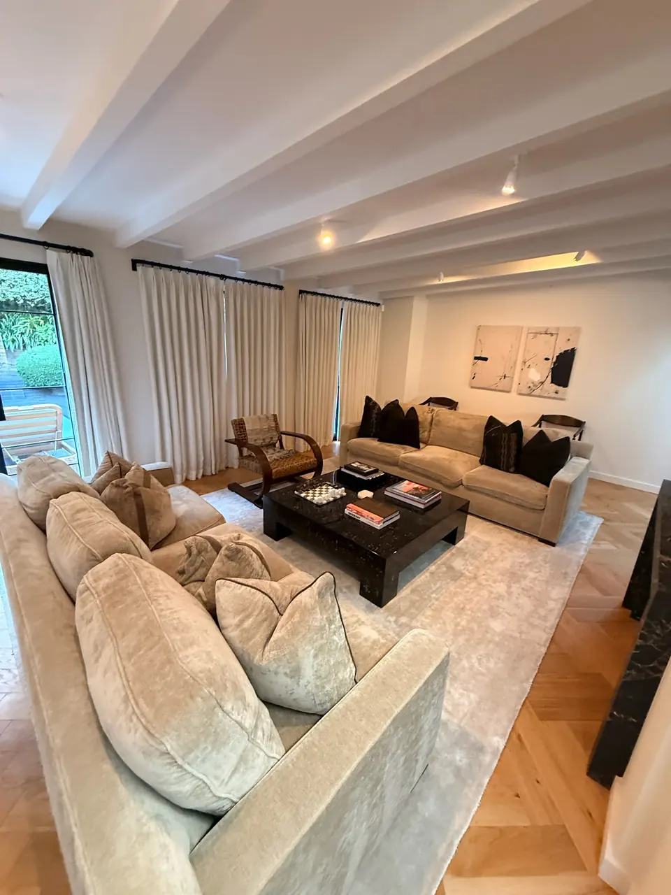 Sunlit living room with a beamed ceiling and cream sofas